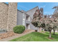 Gray two-story condominium with stone and siding and a well manicured lawn and mature trees at 9797 E Peakview Ave # C1, Englewood, CO 80111