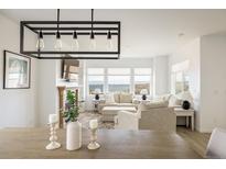 Bright living room with a modern light fixture, cozy fireplace, and large windows showcasing a beautiful view at 16568 W 92Nd Pl, Arvada, CO 80007