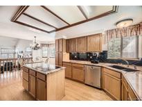 Well-lit kitchen with wood cabinets, stainless steel appliances, and a central island cooktop at 6726 Taft Cir, Arvada, CO 80004