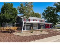 Two-story home boasts a charming exterior with vibrant red garage door and shutters, a covered front porch, and well-manicured landscaping at 12555 W 61St Ave, Arvada, CO 80004