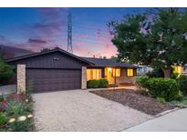 Charming single Gathering home featuring a two car garage, beautiful plants, and exterior brick work at 7382 E Bates Dr, Denver, CO 80231