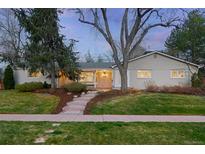Charming single-story home featuring a brick facade, a welcoming front porch, and mature trees in the landscaped yard at 3206 S Clayton St, Denver, CO 80210