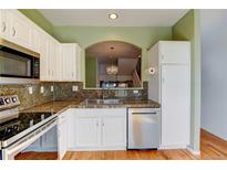 Modern kitchen featuring white cabinets, stainless steel dishwasher and microwave, and a unique backsplash at 9861 E Carolina Pl, Aurora, CO 80247