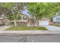 Charming two-story home with a brick and vinyl exterior, complemented by a well-manicured lawn and mature trees at 5241 E 111Th Ct, Thornton, CO 80233