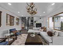 Bright living room with modern decor, fireplace, spiral staircase and antler chandelier at 11987 W Ranch Elsie Rd, Golden, CO 80403