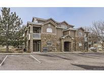 Inviting exterior showcasing stone accents, a private balcony, and ample parking in front of the building at 7440 S Blackhawk St # 15-202, Englewood, CO 80112