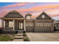 Charming, two-story home featuring stone accents, a covered porch, and an attached two-car garage at 27196 E Alder Dr, Aurora, CO 80016