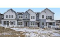 Three-unit townhome building with gray siding, white trim, and front porches at 14556 W 91St Ave # A, Arvada, CO 80005