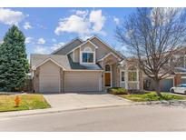 Traditional two-story home with a three-car garage, manicured front yard and mature evergreens at 10470 W Cooper Pl, Littleton, CO 80127