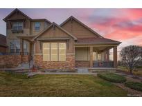 Charming townhome with stone accents, covered porch, and manicured lawn at dusk at 555 Gallegos Cir, Erie, CO 80516