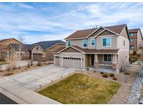 Two-story home with three car garage, neutral colors, landscaping and a inviting front porch at 6065 Clover Ridge Cir, Castle Rock, CO 80104