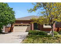 Charming brick home with a well-manicured lawn and a two-car garage on a sunny day at 25077 E Canal Pl, Aurora, CO 80018
