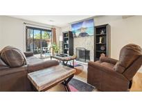 Comfortable living room with fireplace, sliding glass doors to fenced patio, and wood floors at 6462 E Bates Ave, Denver, CO 80222