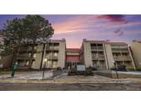 Charming condo building with red roofs and balconies, nestled among mature trees, with a beautiful sunset sky at 14740 E Kentucky Dr # 716, Aurora, CO 80012