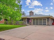 Ranch style home featuring a driveway, brick exterior, a garage door and mature trees at 423 Empire St, Aurora, CO 80010