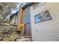 Two-story condo shows a textured facade with multiple windows, a wooden porch, and a stone landscaped path at 4912 Silver Spruce Ln, Evergreen, CO 80439