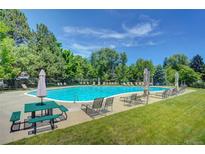 Large community swimming pool with picnic table, lounge chairs and umbrellas at 5050 W 102Nd Ave, Westminster, CO 80031