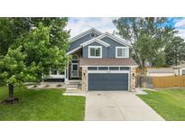 Charming two-story home with blue siding, stone accents, a well-manicured lawn, and an attached two-car garage at 19334 E Prentice Pl, Centennial, CO 80015