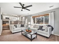 Bright living room with large windows, ceiling fan, and a comfortable sofa with an open view to the kitchen at 2488 W 111Th Pl, Denver, CO 80234