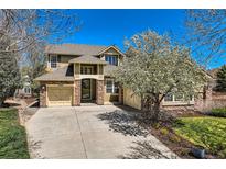 Charming two-story home showcasing a stone-accented facade, three-car garage, and beautifully landscaped front yard at 24487 E Frost Dr, Aurora, CO 80016