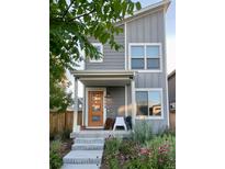 Charming gray two-story home with a welcoming front porch, colorful front yard flowers, and an orange front door at 5863 N Boston St, Denver, CO 80238