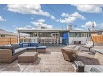 Spacious backyard patio with comfortable seating area, fire pit, and unique hanging chair at 6190 Garrison St, Arvada, CO 80004