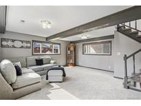 Finished living room features carpet, stairs, wooden beams, and plentiful natural light at 6190 Garrison St, Arvada, CO 80004