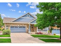 Charming brick home with a well-manicured lawn, a covered porch, and a two-car garage at 8225 W 67Th Pl, Arvada, CO 80004