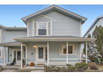 Charming two-story townhome featuring light blue siding, a cozy front porch, and well-maintained landscaping at 6250 Everett Ct # F, Arvada, CO 80004