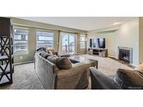 Comfortable living room with a stone fireplace, plush seating, and large windows for natural light at 6250 Everett Ct # F, Arvada, CO 80004