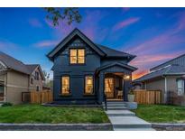 Charming two-story home with dark exterior paint, front porch, landscaped yard, and blue and orange sky at dusk at 2351 N Emerson St, Denver, CO 80205