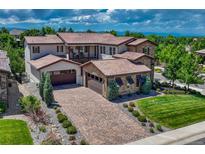 Stunning home with a clay tile roof, stone accents, a brick driveway and lush landscaping at 9343 Vista Hill Ln, Lone Tree, CO 80124