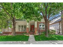 Charming home featuring a brick facade, covered porch, and beautifully landscaped front yard with mature trees at 6900 W Grant Ranch Blvd # 59, Littleton, CO 80123