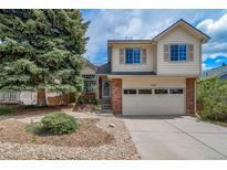 Inviting two-story home with brick accents, large tree, and well-maintained front yard and two car garage at 7072 Palisade Dr, Highlands Ranch, CO 80130