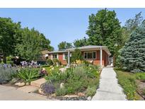 Charming brick home featuring a beautifully landscaped front yard with vibrant flowers and lush greenery at 3380 S Ogden St, Englewood, CO 80113