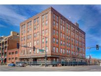 Brick apartment building featuring expansive windows, a covered entrance, and street-level retail space at 2261 Blake St # 5H, Denver, CO 80205