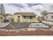 Charming, yellow single-story home featuring a landscaped front yard and a welcoming, covered porch at 1254 S Osceola St, Denver, CO 80219