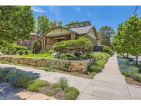 Charming home featuring a beautifully landscaped front yard with a unique stone retaining wall and lush greenery at 4545 King St, Denver, CO 80211
