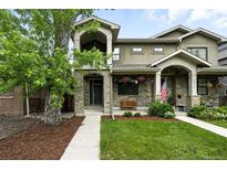 Charming two-story home with stone accents, a covered porch, landscaped yard, and a mature tree in front at 2077 S Clayton St, Denver, CO 80210