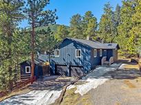 Charming two-story home with blue siding, a two-car garage, and surrounded by lush trees at 30858 Niakwa Rd, Evergreen, CO 80439