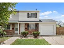 Charming two-story townhome with brick accents, a well-manicured lawn, and a convenient attached garage at 13438 E 13Th Pl, Aurora, CO 80011