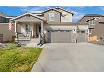 Two-story house with gray siding, stone accents, and a three-car garage at 10167 Vaughn St, Commerce City, CO 80022