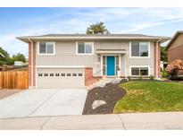 Charming two-story home featuring a blue front door, brick accents, and a well-manicured front yard at 2027 S Welch Cir, Lakewood, CO 80228