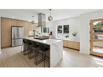 Modern kitchen featuring a large island with seating, stainless steel appliances, and ample natural light at 280 Ammons St, Lakewood, CO 80226