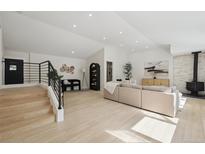Bright, open-concept living room with light wood floors, fireplace, and modern staircase with iron railings at 280 Ammons St, Lakewood, CO 80226