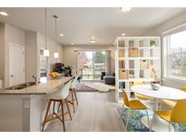 Bright, open-concept living area featuring a kitchen island, dining space, and sliding door to the outside at 655 Stonebridge Dr, Longmont, CO 80503