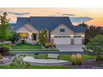 Charming home featuring a manicured lawn, three-car garage, and inviting front porch with stone accents at 27235 E Lakeview Pl, Aurora, CO 80016