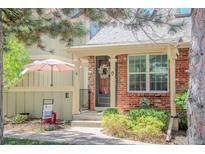 Charming brick home featuring a covered entryway with a wreath-adorned front door and manicured landscaping at 7751 S Curtice Dr # E, Littleton, CO 80120