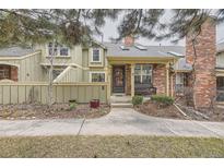 Inviting townhome entrance with brick facade, covered porch, and cozy bench seating at 7751 S Curtice Dr # E, Littleton, CO 80120