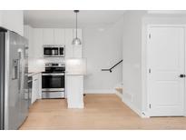 Well-lit kitchen with stainless steel appliances, white cabinetry, and a modern island with stylish pendant lighting at 4232 Jason St # 2, Denver, CO 80211